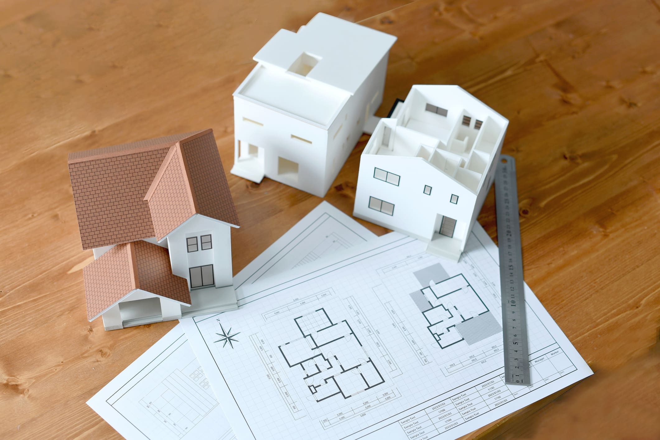 Model houses sitting on a table next to blue prints.