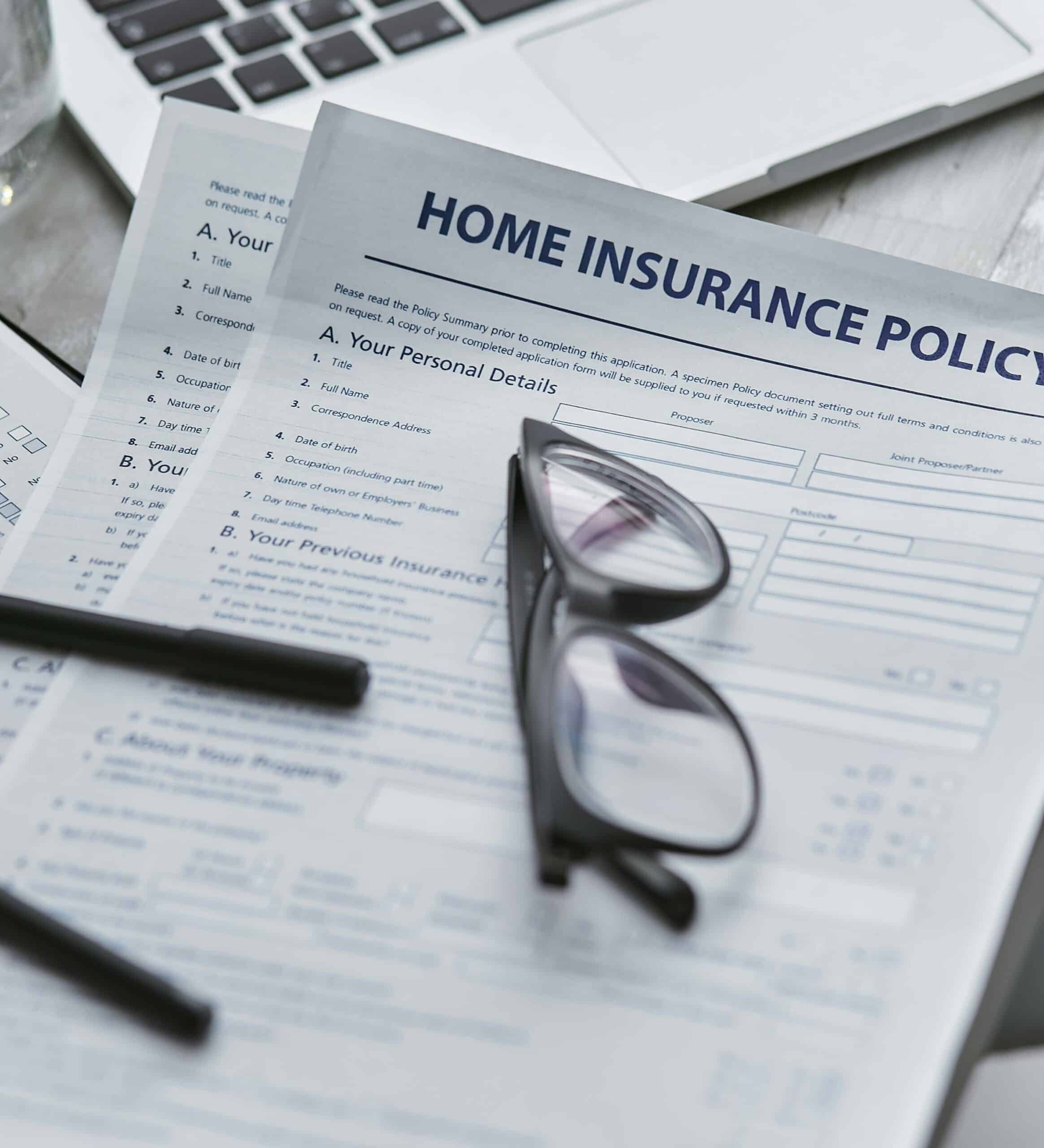 Close view of a blank homeowners insurance policy on a desk with a pair of glasses on top of the paperwork.